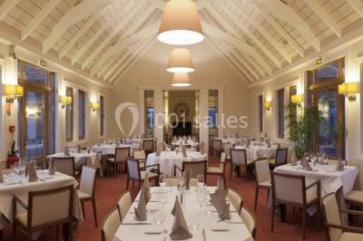 Paysage automnal avec un lac reflétant des arbres aux feuilles rouges et orangées sous un ciel nuageux.