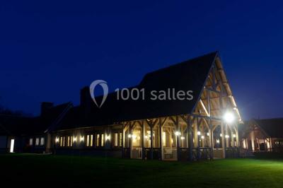 Paysage automnal avec un lac reflétant des arbres aux feuilles rouges et orangées sous un ciel nuageux.