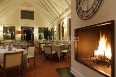 Paysage automnal avec un lac reflétant des arbres aux feuilles rouges et orangées sous un ciel nuageux.