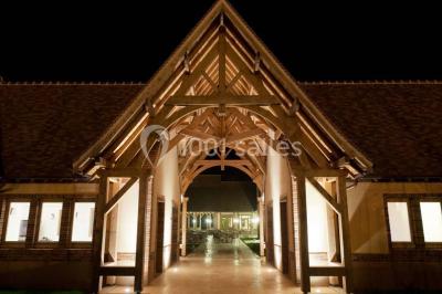 Paysage automnal avec un lac reflétant des arbres aux feuilles rouges et orangées sous un ciel nuageux.
