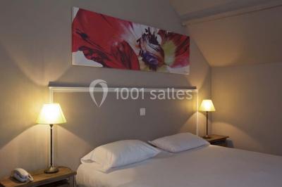 Paysage automnal avec un lac reflétant des arbres aux feuilles rouges et orangées sous un ciel nuageux.