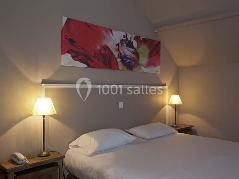 Lit double avec draps blancs, encadré par deux lampes de chevet allumées, dans une chambre aux tons neutres.