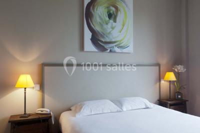 Paysage automnal avec un lac reflétant des arbres aux feuilles rouges et orangées sous un ciel nuageux.