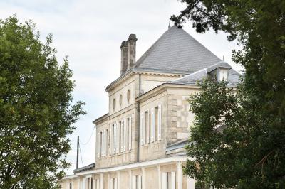 Inscription ’NOUCHET’ gravée sur une façade en pierre et briques, entourée de végétation en arrière-plan.