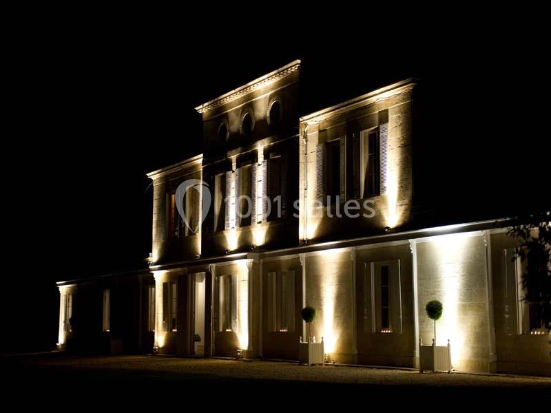Façade d'un bâtiment éclairé par des lumières chaudes, visible de nuit dans un environnement sombre.
