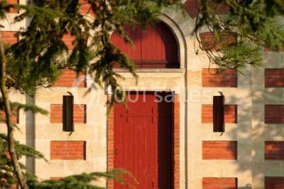 Inscription ’NOUCHET’ gravée sur une façade en pierre et briques, entourée de végétation en arrière-plan.