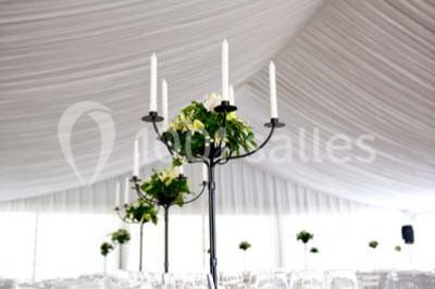 Inscription ’NOUCHET’ gravée sur une façade en pierre et briques, entourée de végétation en arrière-plan.