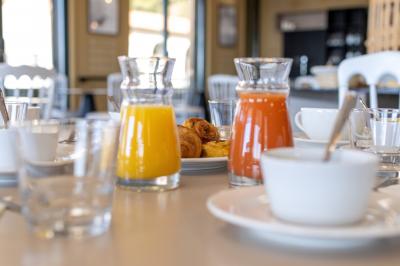 Carafes de jus d'orange et de jus rouge sur une table avec viennoiseries, tasses et verres dans un cadre lumineux.