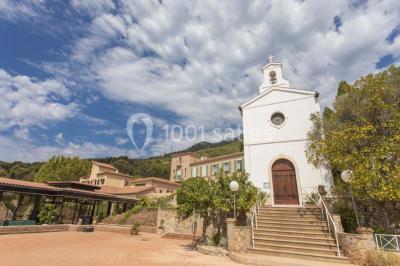 Terrasse en bois aménagée avec des tables, des chaises et des parasols blancs, entourée de végétation.