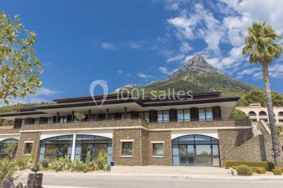Terrasse en bois aménagée avec des tables, des chaises et des parasols blancs, entourée de végétation.