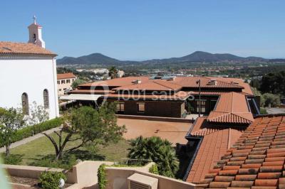 Terrasse en bois aménagée avec des tables, des chaises et des parasols blancs, entourée de végétation.