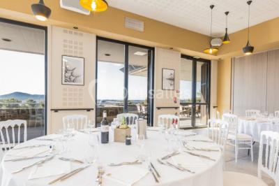 Terrasse en bois aménagée avec des tables, des chaises et des parasols blancs, entourée de végétation.