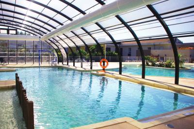 Terrasse en bois aménagée avec des tables, des chaises et des parasols blancs, entourée de végétation.