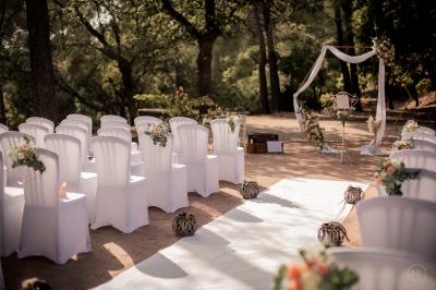 Terrasse en bois aménagée avec des tables, des chaises et des parasols blancs, entourée de végétation.