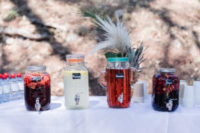 Terrasse en bois aménagée avec des tables, des chaises et des parasols blancs, entourée de végétation.