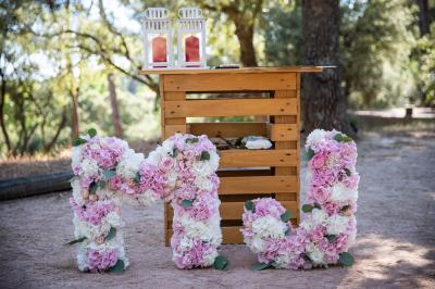 Terrasse en bois aménagée avec des tables, des chaises et des parasols blancs, entourée de végétation.
