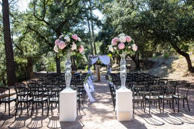 Terrasse en bois aménagée avec des tables, des chaises et des parasols blancs, entourée de végétation.