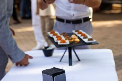 Terrasse en bois aménagée avec des tables, des chaises et des parasols blancs, entourée de végétation.