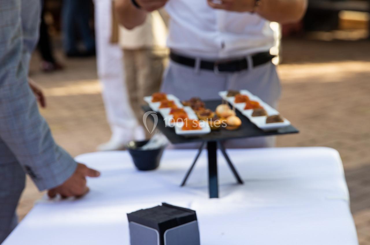 Plateaux de bouchées apéritives variées disposés sur une table lors d'un événement en extérieur.