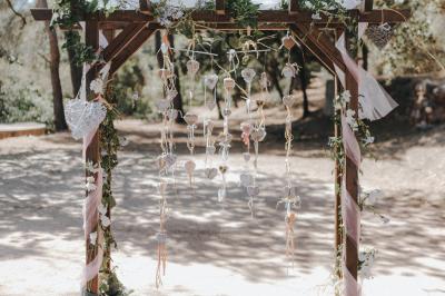 Terrasse en bois aménagée avec des tables, des chaises et des parasols blancs, entourée de végétation.