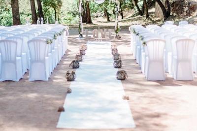 Terrasse en bois aménagée avec des tables, des chaises et des parasols blancs, entourée de végétation.