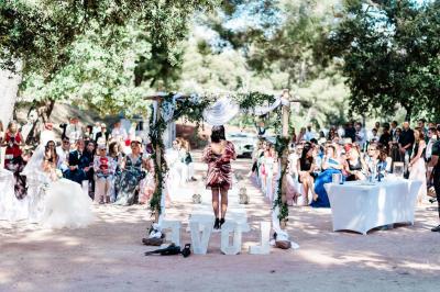 Terrasse en bois aménagée avec des tables, des chaises et des parasols blancs, entourée de végétation.