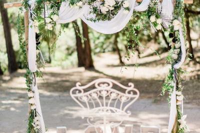 Terrasse en bois aménagée avec des tables, des chaises et des parasols blancs, entourée de végétation.