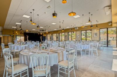 Terrasse en bois aménagée avec des tables, des chaises et des parasols blancs, entourée de végétation.