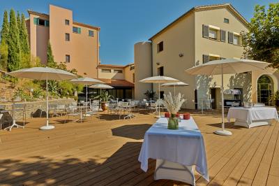 Terrasse en bois aménagée avec des tables, des chaises et des parasols blancs, entourée de végétation.