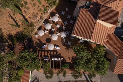Terrasse en bois aménagée avec des tables, des chaises et des parasols blancs, entourée de végétation.