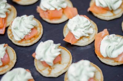 Terrasse en bois aménagée avec des tables, des chaises et des parasols blancs, entourée de végétation.