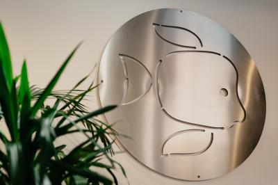 Miniature Location salle La Mulatière (Rhône) - Aquarium de Lyon #21 Plaque métallique ronde avec un motif de poisson découpé, accrochée à un mur clair, partiellement cachée par une plante…