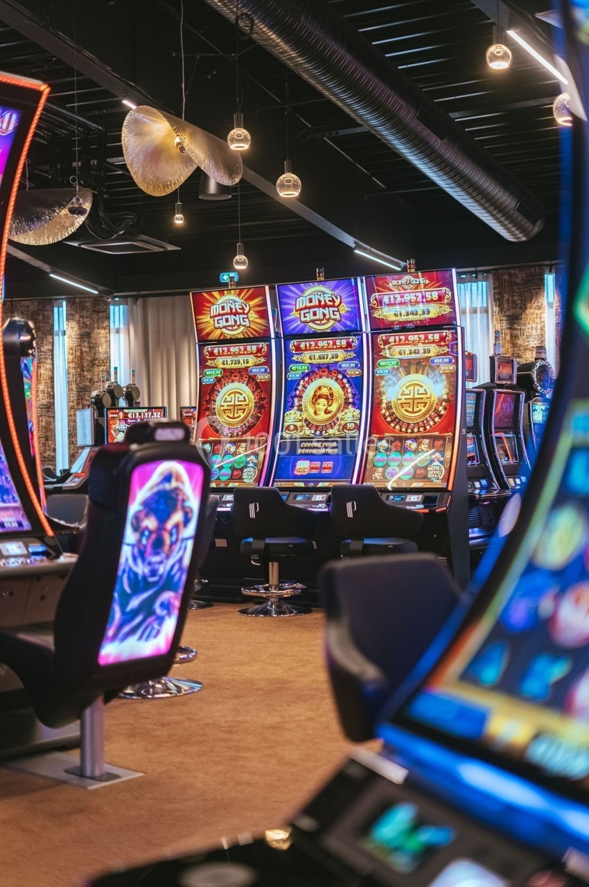 Salle de casino avec plusieurs machines à sous lumineuses alignées dans un espace moderne et éclairé.