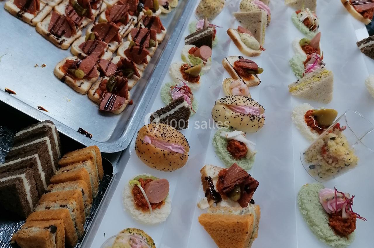 Plateaux de bouchées apéritives variées disposées en rangées sur une table, prêtes pour un service traiteur.