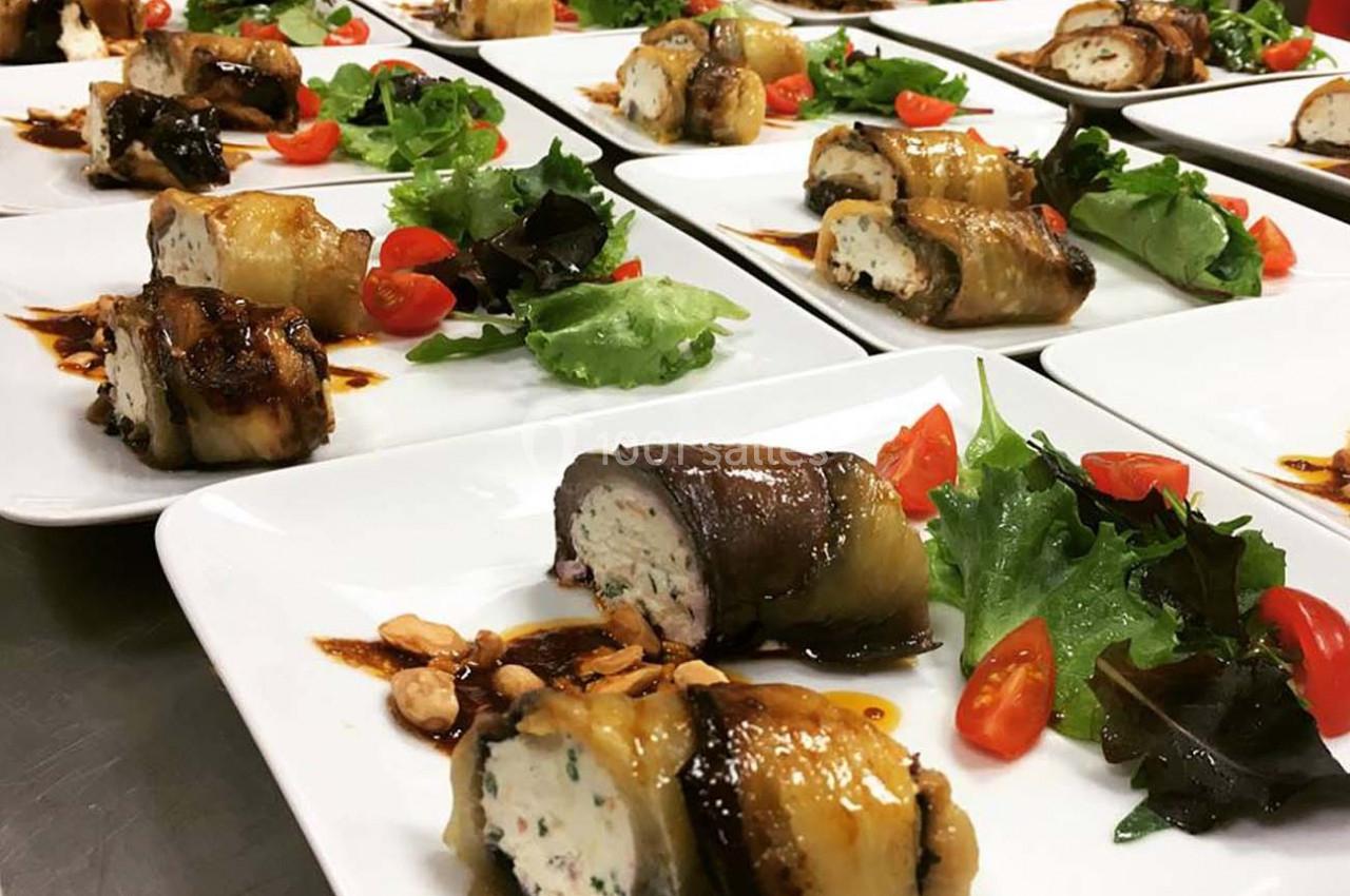 Assiettes dressées avec des roulés d'aubergine farcis, salade verte, tomates cerises et sauce balsamique.