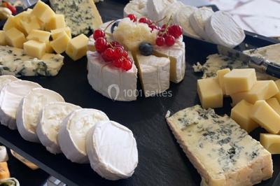Plateau de fromages variés comprenant des morceaux de brie, de fromage bleu, de chèvre et des cubes de fromage à pâte dure.