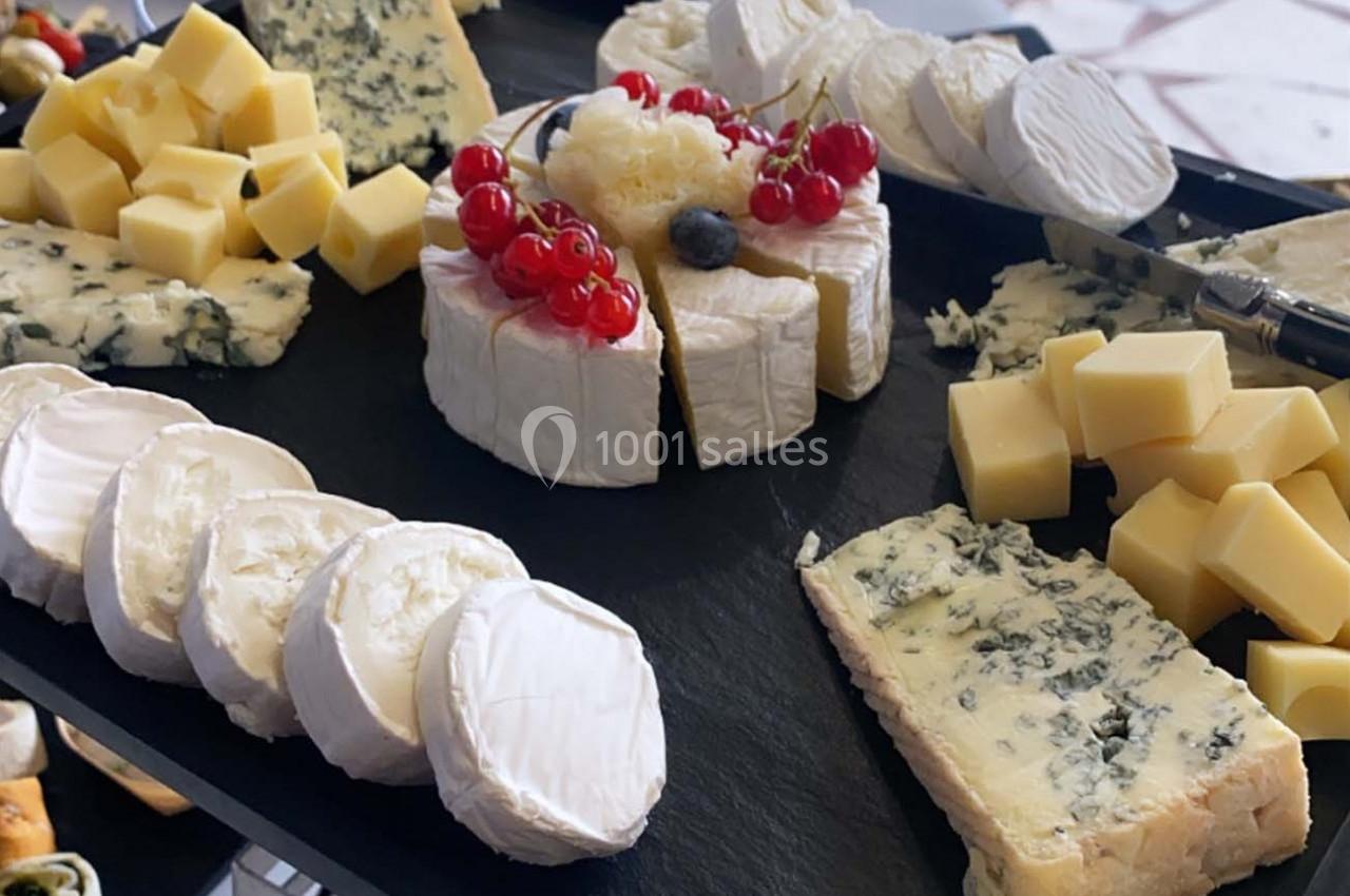 Plateau de fromages variés comprenant des morceaux de brie, de fromage bleu, de chèvre et des cubes de fromage à pâte dure.