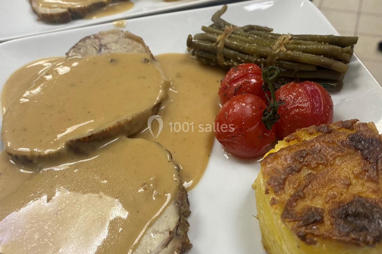 Assiette composée de rôti en sauce, gratin de pommes de terre, haricots verts et tomates cerises rôties.