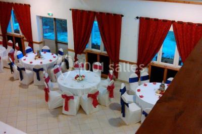 Portail en fer forgé rouge avec piliers blancs, donnant sur une allée menant à une maison entourée d'arbres.