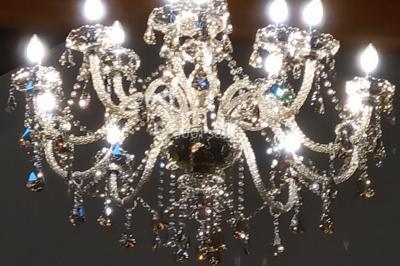 Portail en fer forgé rouge avec piliers blancs, donnant sur une allée menant à une maison entourée d'arbres.