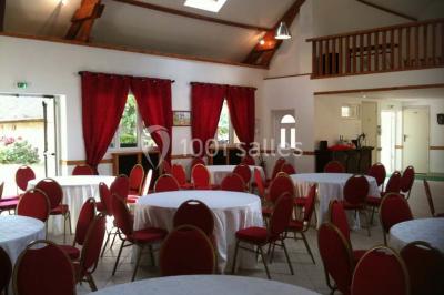 Portail en fer forgé rouge avec piliers blancs, donnant sur une allée menant à une maison entourée d'arbres.