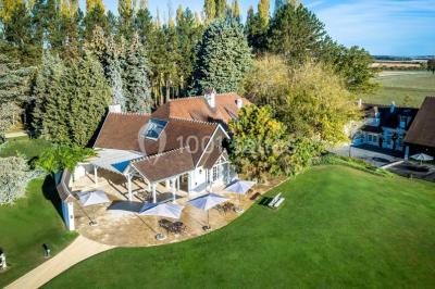 Pont éclairé et kiosque en bois près d'une fontaine illuminée, entourés d'arbres dans un parc nocturne.