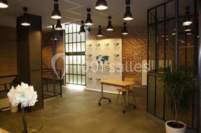 Salle de conférence vide avec des rangées de chaises en bois, un écran de projection et des tableaux accrochés au mur.