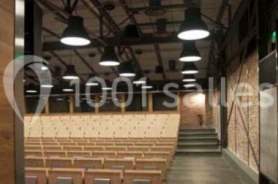 Salle de conférence vide avec des rangées de chaises en bois, un écran de projection et des tableaux accrochés au mur.