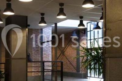 Salle de conférence vide avec des rangées de chaises en bois, un écran de projection et des tableaux accrochés au mur.