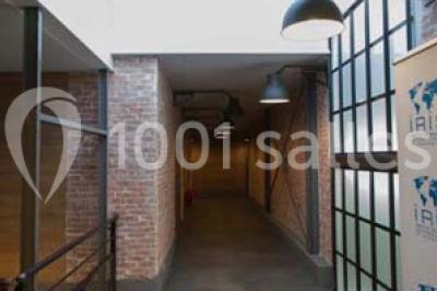 Salle de conférence vide avec des rangées de chaises en bois, un écran de projection et des tableaux accrochés au mur.