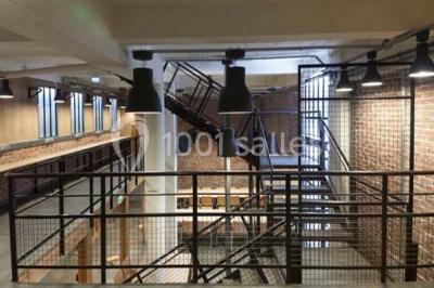 Salle de conférence vide avec des rangées de chaises en bois, un écran de projection et des tableaux accrochés au mur.