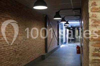 Salle de conférence vide avec des rangées de chaises en bois, un écran de projection et des tableaux accrochés au mur.
