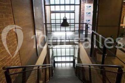 Salle de conférence vide avec des rangées de chaises en bois, un écran de projection et des tableaux accrochés au mur.