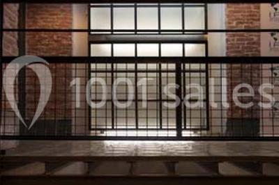 Salle de conférence vide avec des rangées de chaises en bois, un écran de projection et des tableaux accrochés au mur.